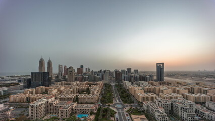 Fototapeta na wymiar Panorama of skyscrapers in Barsha Heights district and low rise buildings in Greens district aerial night to day timelapse.