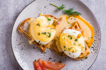 Closeup of eggs benedict and bacon on a crispy waffle for homemade breakfast. Top view