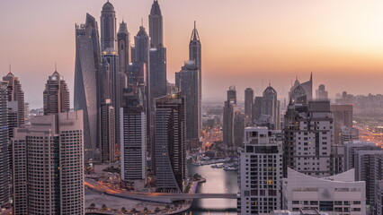 View of various skyscrapers in tallest recidential block in Dubai Marina aerial night to day timelapse