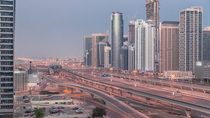 Naklejka na ściany i meble Dubai Marina skyscrapers and Sheikh Zayed road with metro railway aerial night to day timelapse, United Arab Emirates