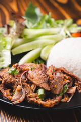 Spicy Grilled Beef or pork and chicken Thai style salad (Red onion, Spring onion, Rice powder, Lettuce Chili powder )in a bowl with rice, called as Nam Tok, Jaew dipping sauce and vegetables