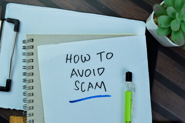 Concept of How to Avoid Scam write on sticky notes isolated on Wooden Table.