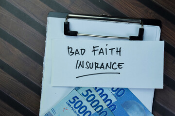 Concept of Bad Faith Insurance write on sticky notes and Indonesian Currency isolated on Wooden Table.