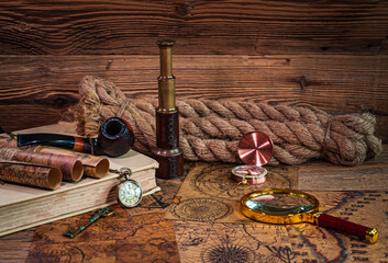 Old objects, book, magnifying glass, compass, pocket watch, spyglass, thick rope, tobacco pipe, old key lying on old maps