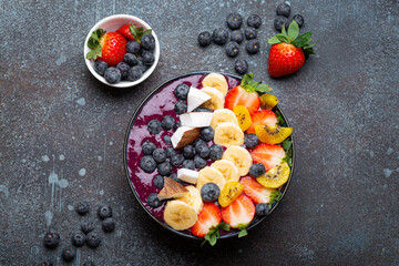 Healthy summer acai smoothie bowl with chia seeds, fresh banana, strawberry, blueberry, cocos, kiwi...