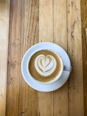 A cup of coffee latte on a wooden table. A mug of flat white coffee, latte, cappuccino on a wooden background. Coffee art. Heart flower swan shape latte art