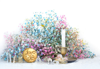 Moon amulet, clear crystals, candlestick and flowers on table close up, blurred light background....