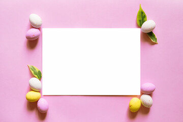 Naklejka na ściany i meble Happy easter decor concept. Blank greeting card, invitation mockup. Festive pastel pink background, chocolates in the form of Easter eggs. Copy space, flat lay, top view.