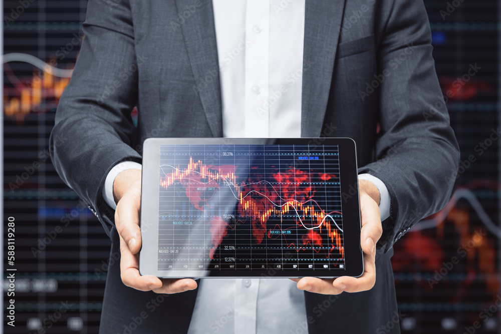 Poster close up of hand holding and showing tablet with falling red crisis forex chart on dark grid backgro