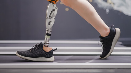 Woman with prosthetic leg using walking on treadmill while working out in gym.