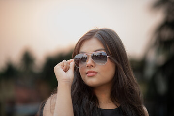 Portrait of a young beautiful teenage girl in sunglasses in mid noon 