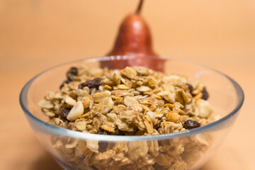 muesli in a glass plate on the background red pear