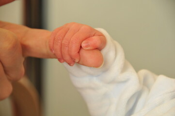 Baby hand clutches its mummy's finger