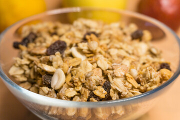 muesli in a glass plate in the background red pear, yellow block, lemon