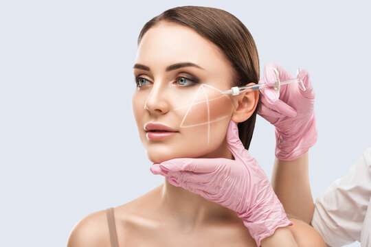 The cosmetologist makes injections of the cheekbones of a beautiful woman. Women's cosmetology in a beauty salon.
