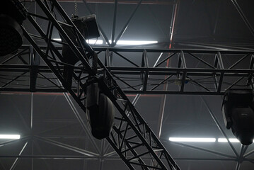 A concert lighting device on a dark background hangs on a truss.