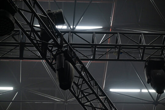 A concert lighting device on a dark background hangs on a truss.