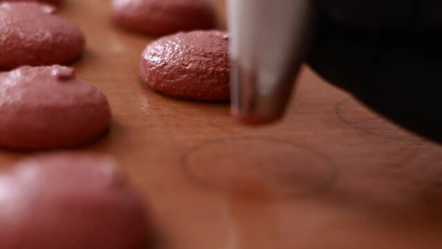 professional chef making base for preparation macaron dessert. Close-up of extruding brawn creme from piping bag on tray For baking base of macaroon dessert. Concept Of Baking, Cooking. close up.