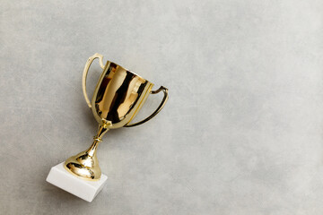 Simply flat lay design winner or champion gold trophy cup on concrete stone grey background....