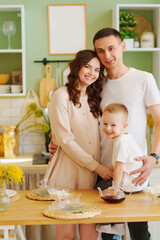 Obraz na płótnie Canvas a loving family. pregnant mom, son and dad In the kitchen. a cozy house 