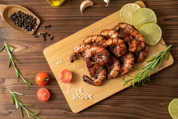 Grilled fried shrimp on a bamboo board wooden table with vegetables and spices