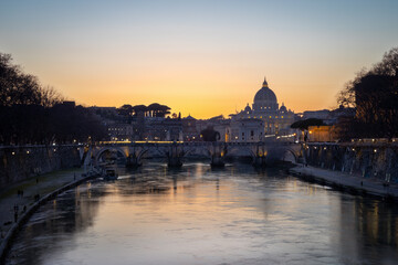Naklejka premium ityscape with Sant Angelo bridge and St. Peter's cathedral at nightfall with city lights in Rome, Italy