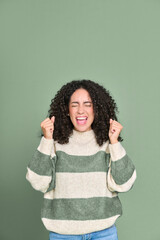 Young happy latin woman winner screaming celebrating win isolated on green background. Excited...