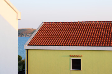 Light yellow house. Seashore. Open air. Croatia. Summer landscape. Tiled building roof. Lonely window. White wall.