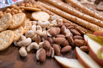 Assorted Nutty Delights- A Close-Up of a Snack Plate Featuring Peanuts, Cashews, Almonds, Apples, Crackers, and Sesame Sticks