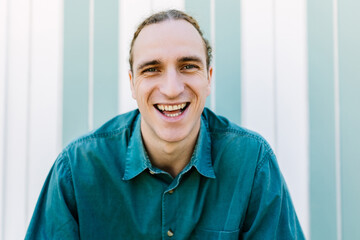 Joyful young adult nordic caucasian boy in summer clothes smiling at camera outdoors