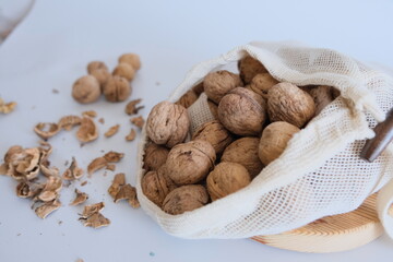 Cotton mesh bag with walnuts and walnut kernels, shells  on a white background.