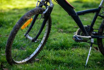 Dirty bike wheel. Bicycle rides, travel, outdoor activities. The bike is on the green grass.