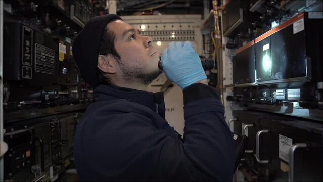 Aircraft Technician inspecting and working in the main electronics bay of a 757 commercial airplane.