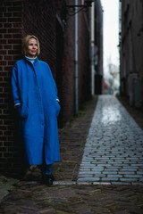 Fototapeta premium Weekend in the Netherlands, a woman in a blue coat on the background of the streets of the city. Rest, travel in Europe.