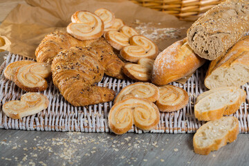 Fototapeta na wymiar Assortment of fresh baked goods on wicker mat with basket on wooden background