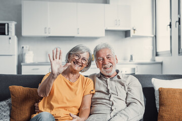 Obraz na płótnie Canvas Sixty years couple, elderly parents communicates with grown up children using modern technologies makes video call, wave hands gesture of hello or goodbye sign, older generation and internet concept.