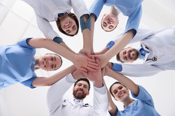 Obraz na płótnie Canvas Team of medical doctors putting hands together indoors, bottom view