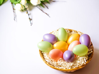 Colorful Easter eggs in a basket. Bouquet of tulips and willow branches. Congratulatory background.