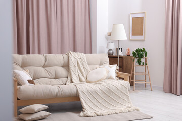 Comfortable sofa, cushions and blanket in cozy room. Interior design
