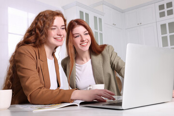 Beautiful young sisters spending time together in kitchen