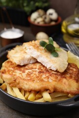 Tasty soda water battered fish and potato chips on wooden table, closeup