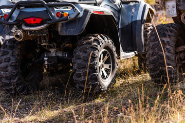 Fototapeta na wymiar Close-up tail view of ATV quad bike on dirt country road. Dirty wheel of AWD all-terrain vehicle. Travel and adventure concept.