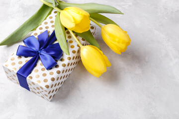 Gift box with blue ribbon and yellow tulips