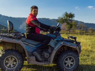 A man driving a quad ATV motorcycle through beautiful meadow landscapes