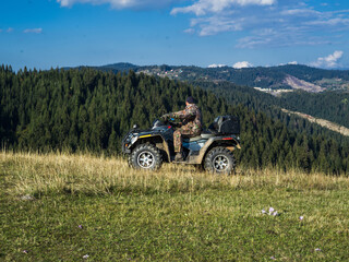 A man driving a quad ATV motorcycle through beautiful meadow landscapes