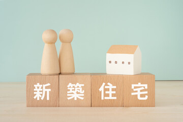 新築住宅と書かれたブロックと人形と家
