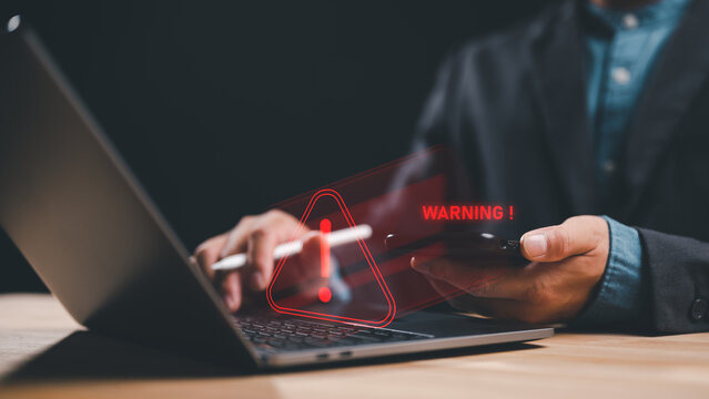Businessman or it staffs, programmer, developer using computer laptop with triangle caution warning sign for notification error and maintenance concept, System warning hacked alert, cyberattack.