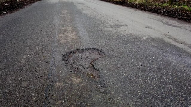 Large pothole in a rural road which caused a near fatal accident in the county of Rutland in England, United Kingdom