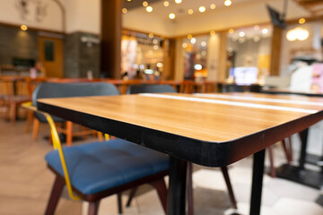 Blurry cafe, restaurant or coffee shop background and perspective view of wooden table corner.