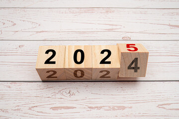 Countdown to 2025. Flipping 2024 to 2025 on wooden cubes on a wooden table
